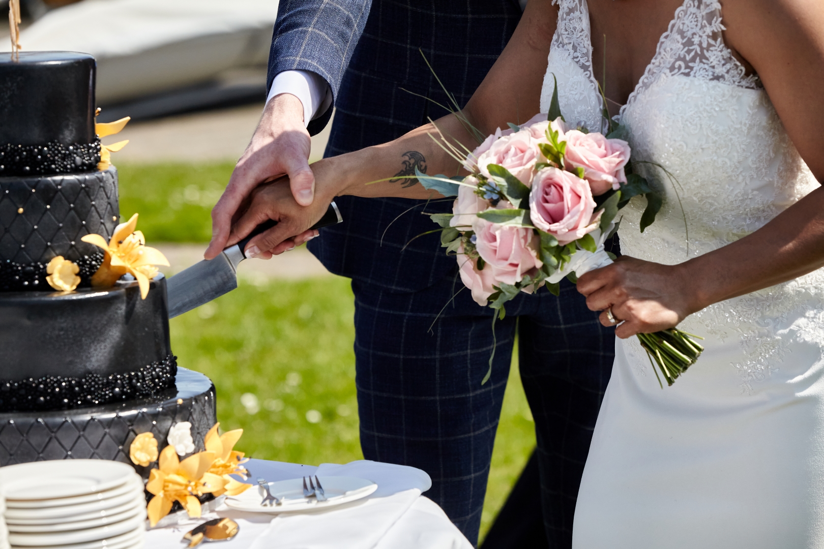 Bruiloft taart aansnijden met bloemen in de hand
